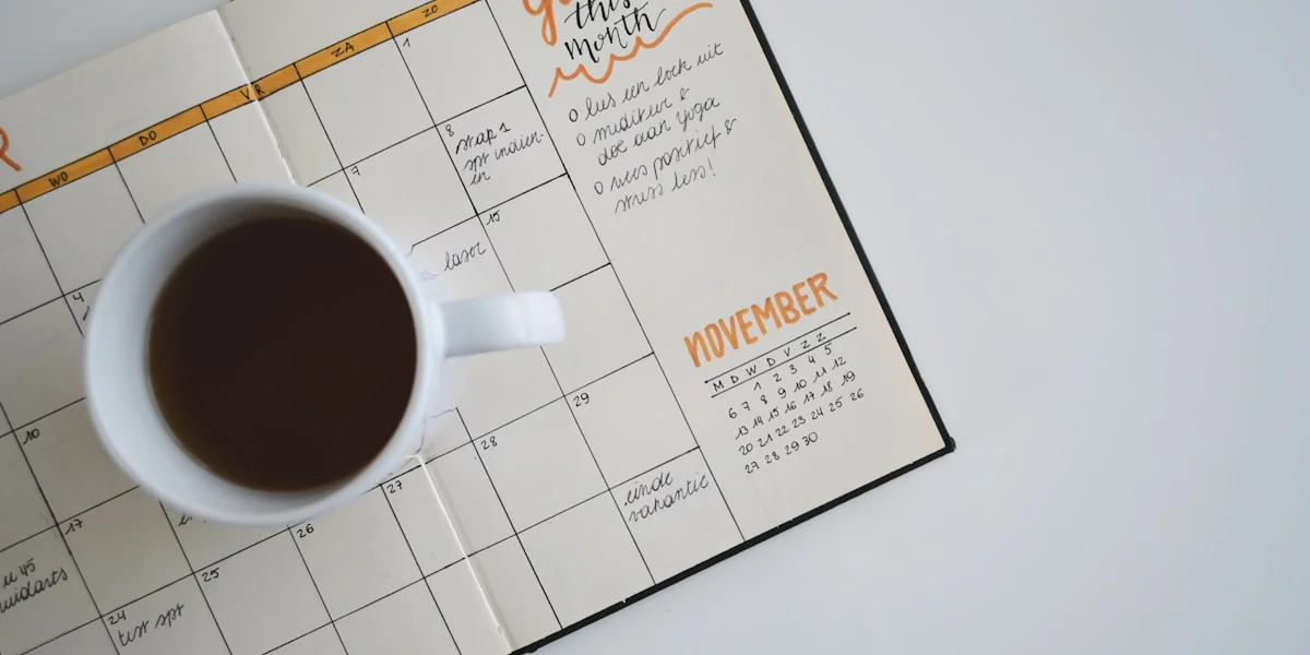 Open planner notebook with pencils and a calendar on a wooden desk